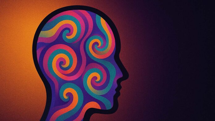 Ilustracja psychodeliczna przedstawiająca sylwetkę ludzkiej głowy wypełnioną kolorowymi, spiralnymi wzorami, symbolizująca badania nad zastosowaniem LSD w leczeniu zaburzeń lękowych.
